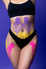 Obraz na płótnie Canvas Cosmetology kinesio tapes on young woman waist and legs. Body care modern treatment for tighten skin muscle tissue and improve blood circulation. Anti-cellulite procedure in beauty center. legs. Sport