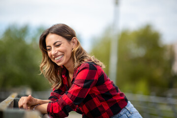 happy young woman leaning against railing outside