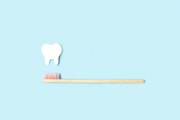 Cepillo de dientes y diente blanco sobre un fondo celeste liso y aislado. Vista superior y de cerca. Copy space. Concepto: medicina odontología