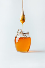 close-up on a jar of honey and a whisk for honey with dripping honey on a white background