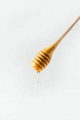 close-up of a honey spindle on a spoon with a dripping drop of honey