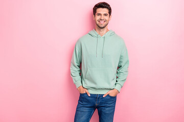 Photo of cheerful positive guy wear stylish khaki hoodie hands pockets confident successful boyfriend company owner smiling isolated on pink color background