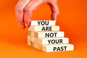 You are not your past symbol. Concept words You are not your past on wooden blocks. Businessman hand. Beautiful orange table orange background. Business and you are not your past concept. Copy space.