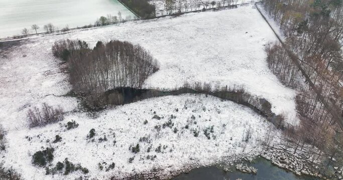 Aerial view of grassland, forest and lakes in nature area Witte Veen with snow during light snow shower, Twente, Overijssel, Netherlands