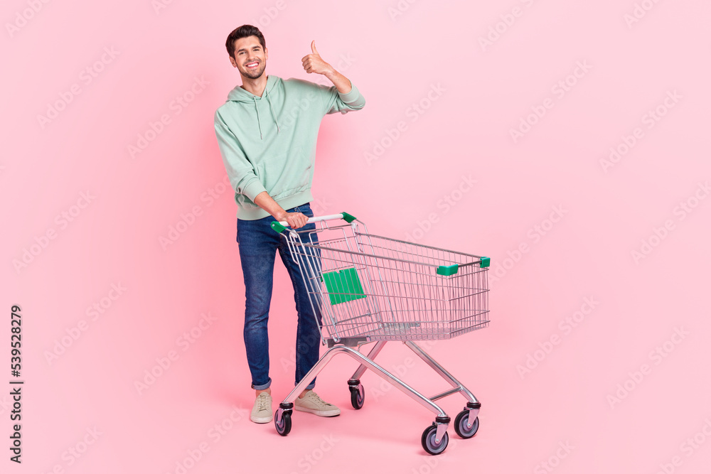 Poster full length photo of funny positive satisfied man stylish clothes hold pushcart hand thumb up empty 