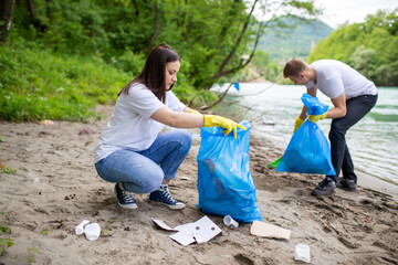 Young people collecting waste on river bank