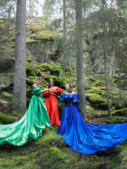 Three beautiful girls in long dresses on the background of the forest. Forest nymphs.