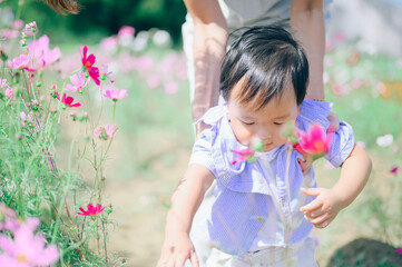 mother with little child in white blooming garden. woman with son in green leaves,happy family outdoors in spring