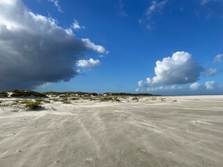 Dunkle Wolkengebilde hängen über der Nordseeinsel Baltrum. Derweil fliegen Sandkörner über den...