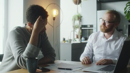 Financial planner explaining documents to young man during consultation at home