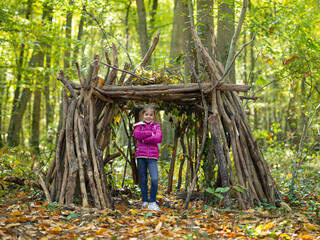 une petite fille et sa cabane en bois en forêt - obrazy, fototapety, plakaty