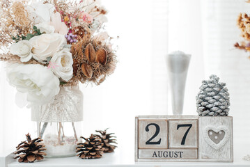 August 27th. August 27 wooden cube calendar with blur objects on background.