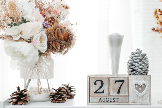 August 27th. August 27 wooden cube calendar with blur objects on background.