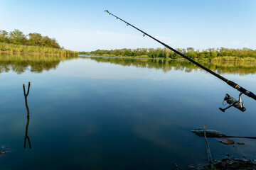 Spinning rod on the riverbank, earlier in the morning. The concept of fishing hobby, sports and...