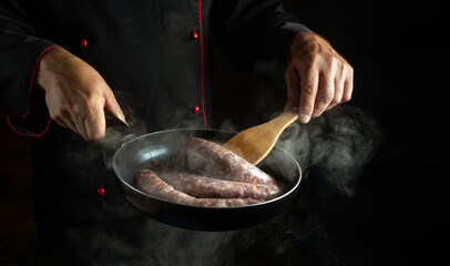 Meat juicy sausage fry. The chef prepares a delicious lunch in a steamed hot pan. Free space for advertising