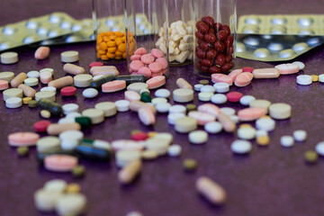Medical bottles and medication pills spilling out on to purple background