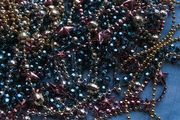 many different festive, New Year's, Christmas beads and garlands in one pile, skein, lie on the floor on the table for the background. Pink, blue, gold and yellow colors