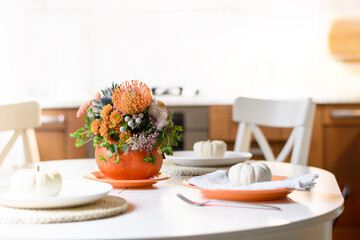Thanksgiving day table setting decoration centerpieces with orange flowers in pumpkins.