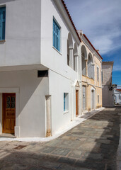 Fototapeta na wymiar Greece. Andros island Chora town Cyclades. Cobblestone alley old houses sun blue sky. Vertical