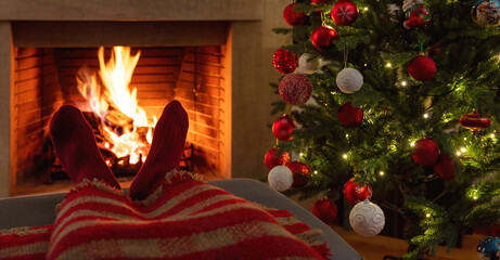 Man relaxing at the burning fireplace, Christmas tree decoration. Winter holiday relaxation at home