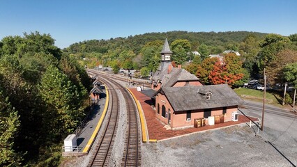 Fototapeta na wymiar Rail train station depot in Point of Rocks Maryland beside forest hillside, Potomac River and small town American neighborhoods