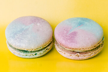 Tasty colorful macaroon. Two blue and pink macaroons on a yellow background. Most delicate cake is a cookie made of two smooth halves, fastened with fillings. French pastry made from egg whites.
