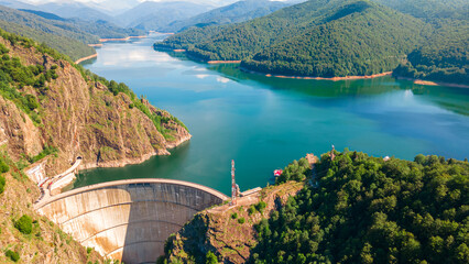 Aerial photography of Vidraru dam, in Romania. Photography was shot from a drone from above canyon at Vidraru lake with the dam and the lake in the view and mountains in the background.