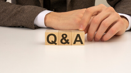 hand holding wooden cube blocks with text q and a - Question and Answer - on white table background. financial, marketing and business concepts