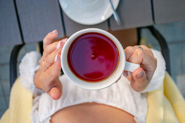 The girl is sitting in a summer cafe.