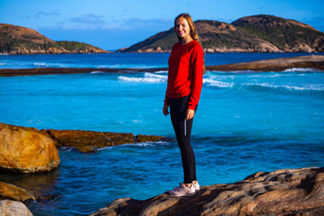 beautiful long-haired girl stands on the rocks above the ocean admiring the sunset; sunset on lucky...