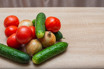 Fresh vegetables on a wooden table. Tomatoes, cucumbers, onions