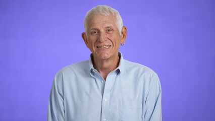 Obraz premium Portrait of a senior old man with gray hair looking at the camera. Happy elderly man smiling. Grandpa is happy to live, a healthy lifestyle. Close-up