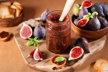 Fig jam or fig marmalade on wooden board with fresh, ripe figs