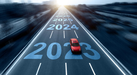Blurred motion highway with single red car, and number 2023, 2024 to 2028 on the road