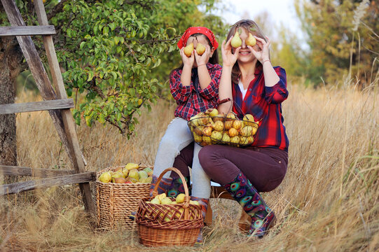 Mother And Daughter Holding Pears As Glasses In Front Of Eyes