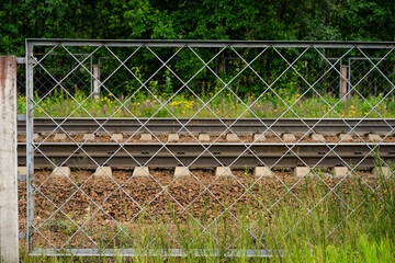 Railway rails fenced with metal mesh. The danger of playing on railway tracks.Freight transportation by train.
