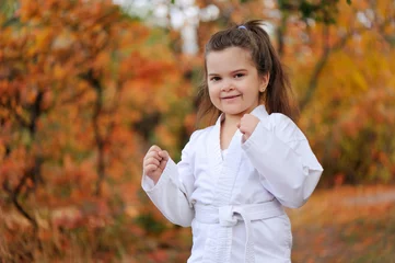 Fotobehang Smiling girl at the martial arts training in the fall park ©  Tatyana Kalmatsuy