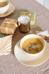 Pumpkin soup on linen tablecloth. Cozy home atmosphere.  Aesthetic dinner. Festive table setting for family event celebration.