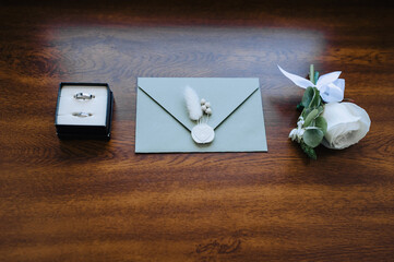Wedding details and accessories close-up: boutonniere, rings in a box, an envelope with a seal with...