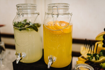 Lemonade drink with ice, lemon, and mint leaves in a jug on the table. Jar or pitcher with juice....