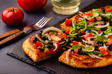 Homemade vegan pizza with tomatoes, peppers, olives, onions.