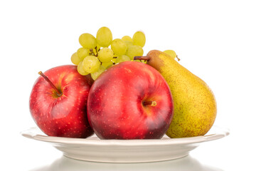 Two red apples, a pear and grapes on a clay plate, macro, isolated on a white background.