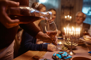 Close up of man serving Kosher wine during Hanukkah family dinner.