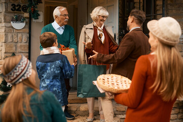 Happy multigeneration family greeting at the doorstep while gathering for Thanksgiving.