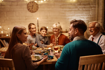 Happy father and daughter talking during family meal at dining table on Thanksgiving.
