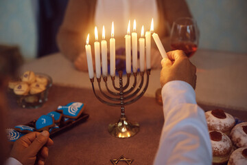 Close up of senior man lighting menorah during Jewish festival of lights.