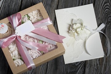 Homemade marshmallows in a gift box. Tied with ribbon. Zephyr flowers. Homemade greeting card in white. With decorative elements. Ribbons, flowers and leaves are attached to cardboard.