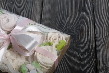 Homemade marshmallows in a gift box. Tied with ribbon. Zephyr flowers. On black pine boards. Taken from above.