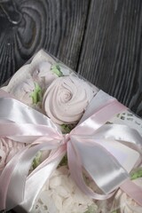Homemade marshmallows in a gift box. Tied with ribbon. Zephyr flowers. On black pine boards. Taken from above.