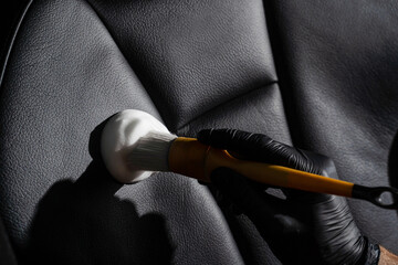 Naklejka premium Process of foam and detergent cleaning leather seat using brush. Worker in auto cleaning service clean car inside. Car interior detailing.